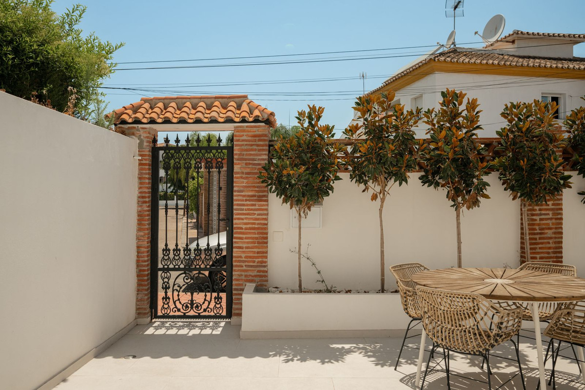 Wrought-iron gate in a brick surround leading from the patio to the street