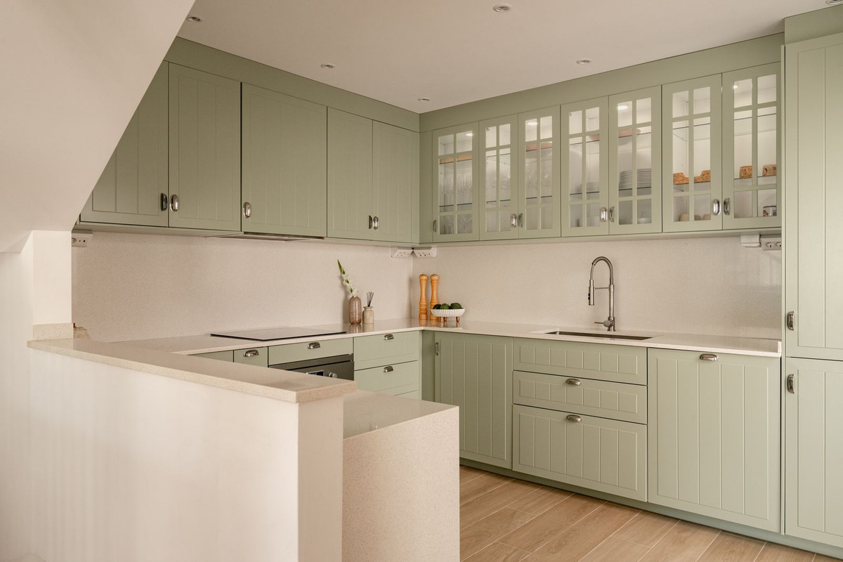 Kitchen in full with sage-green cabinetry, glass-front cabinets and composite worktop