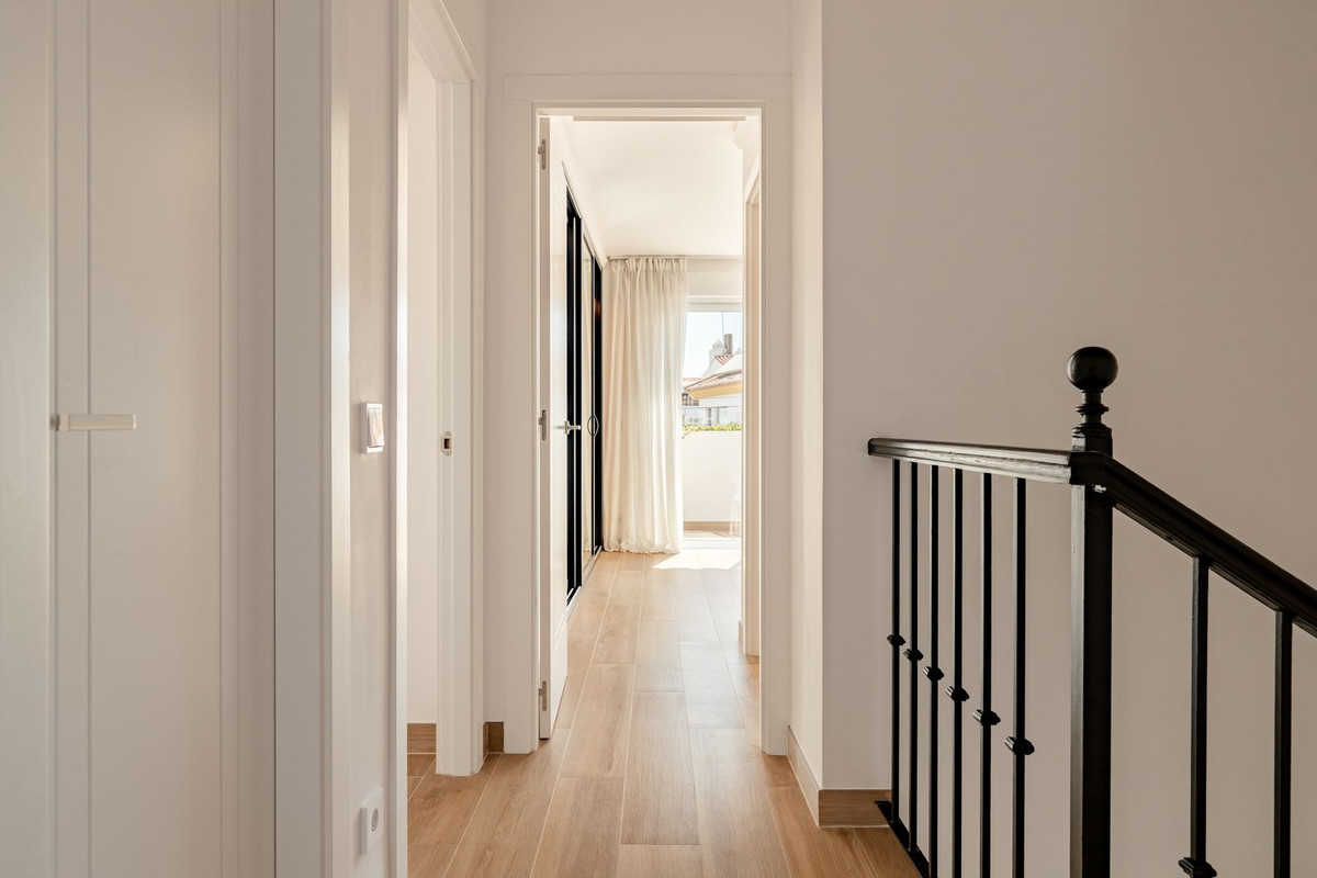 Upper-floor corridor with light-filled bedroom visible through an open door